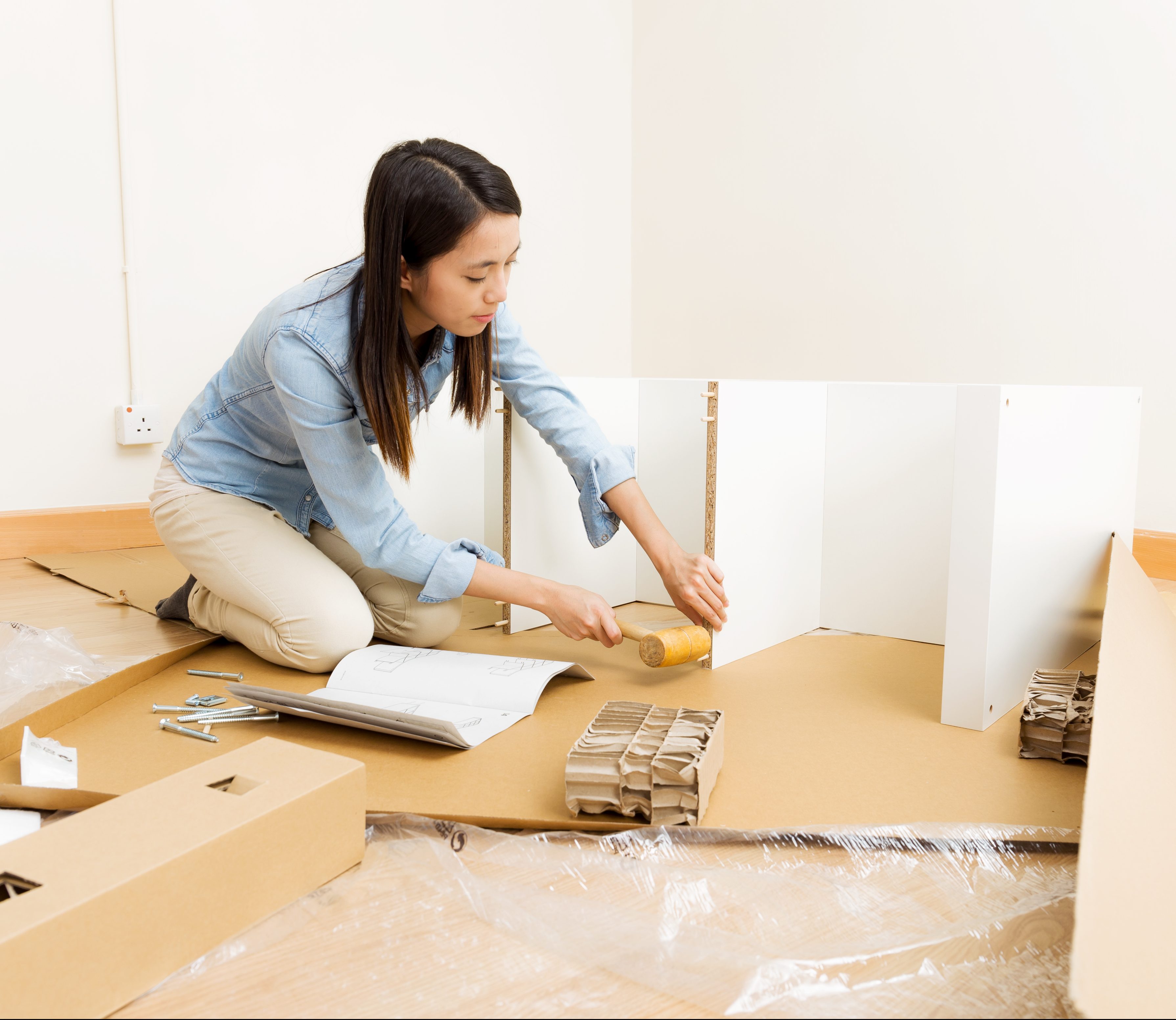 Asian woman using hammer for assembling furniture