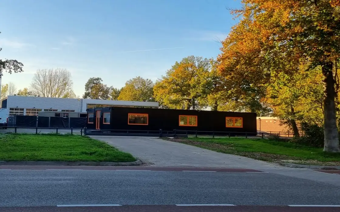 De vestiging van Truckit op het Nudepark in Wageningen: de zwarte kantoorunit met oranje kozijnen, gezien vanaf de weg
