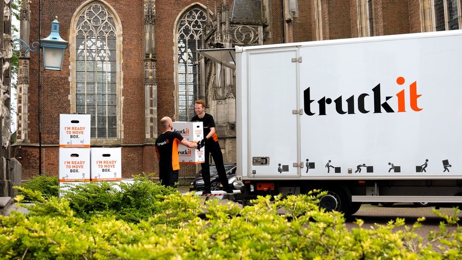 Verhuizers van Truckit laden verhuisdozen bij de verhuiswagen in een historische straat