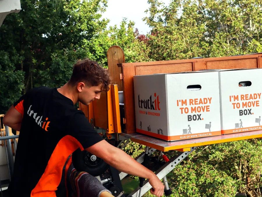 Verhuizer van Truckit bedient de verhuislift met verhuisdozen op het plateau