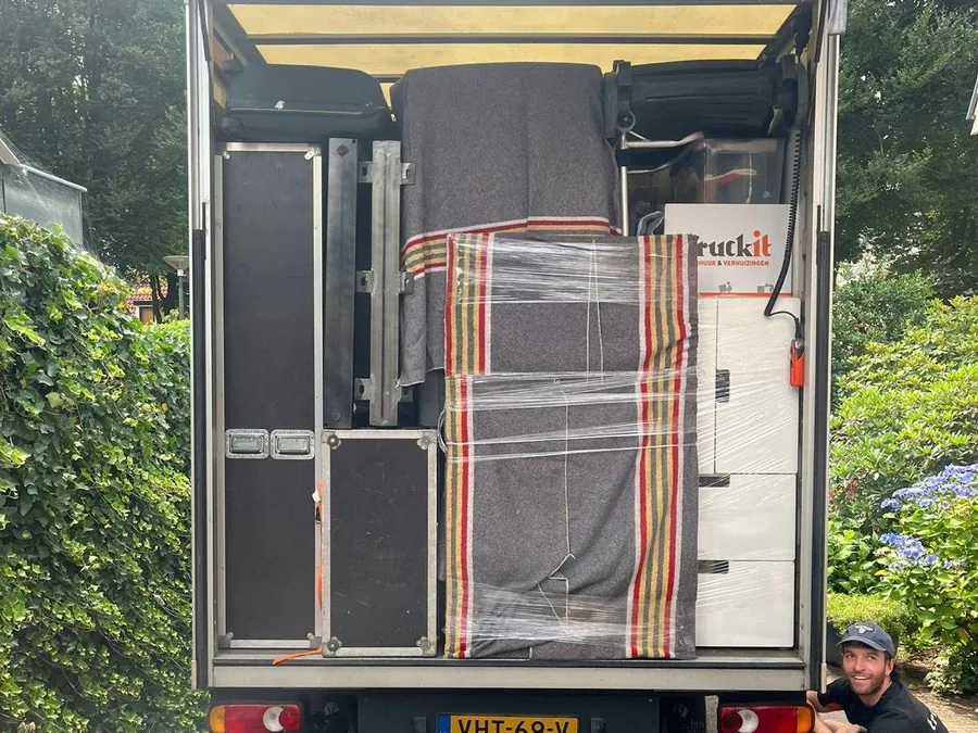 Verhuiswagen van Truckit van achteren, tot het dak geladen met ingepakte meubels