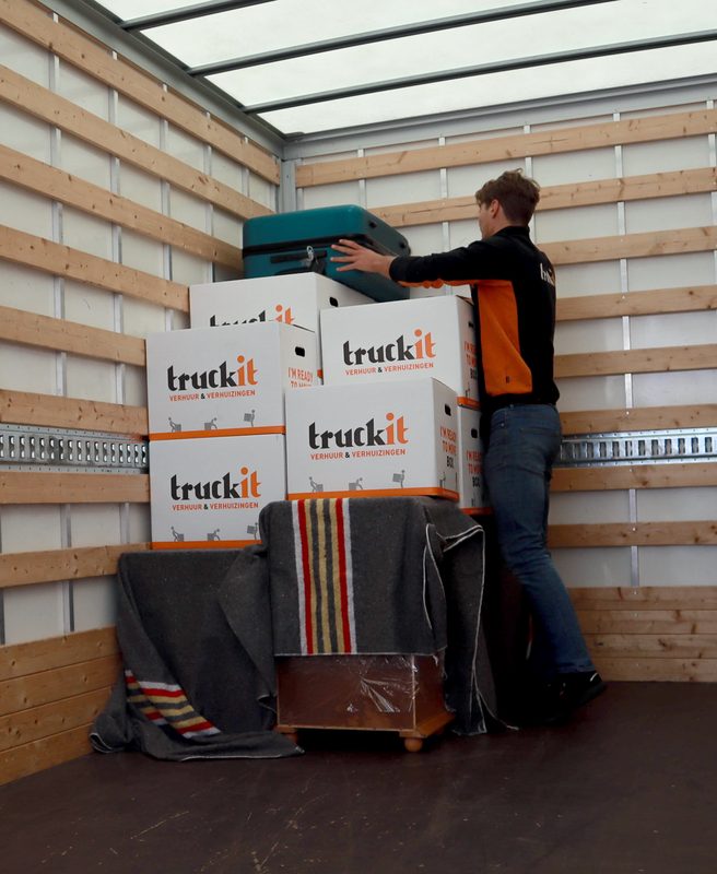 Verhuizer van Truckit stapelt verhuisdozen in de laadbak van de verhuiswagen