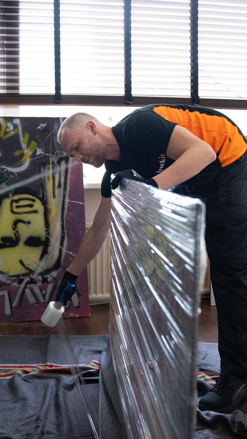 Verhuizer van Truckit wikkelt een groot meubelstuk in