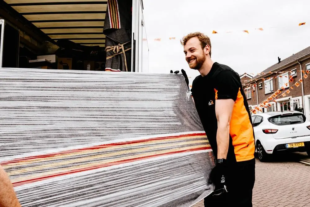Verhuizer van Truckit draagt een ingepakt matras naar de verhuiswagen