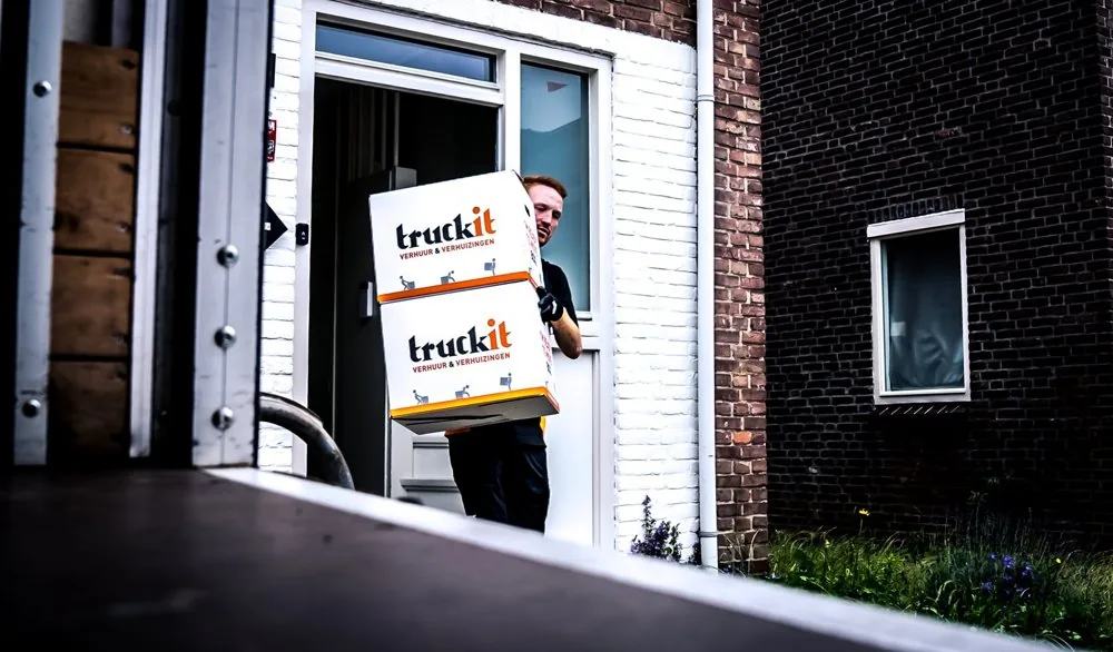 Verhuizer van Truckit draagt verhuisdozen een woning uit