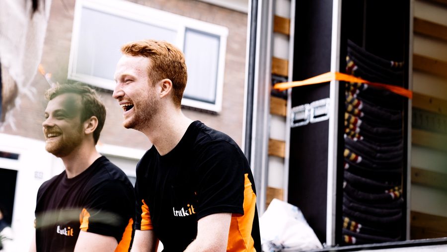Twee verhuizers van Truckit lachen samen bij de wagen