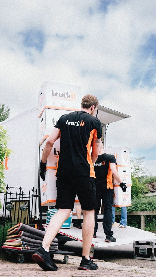 Verhuizers van Truckit dragen verhuisdozen onder een zomerse lucht