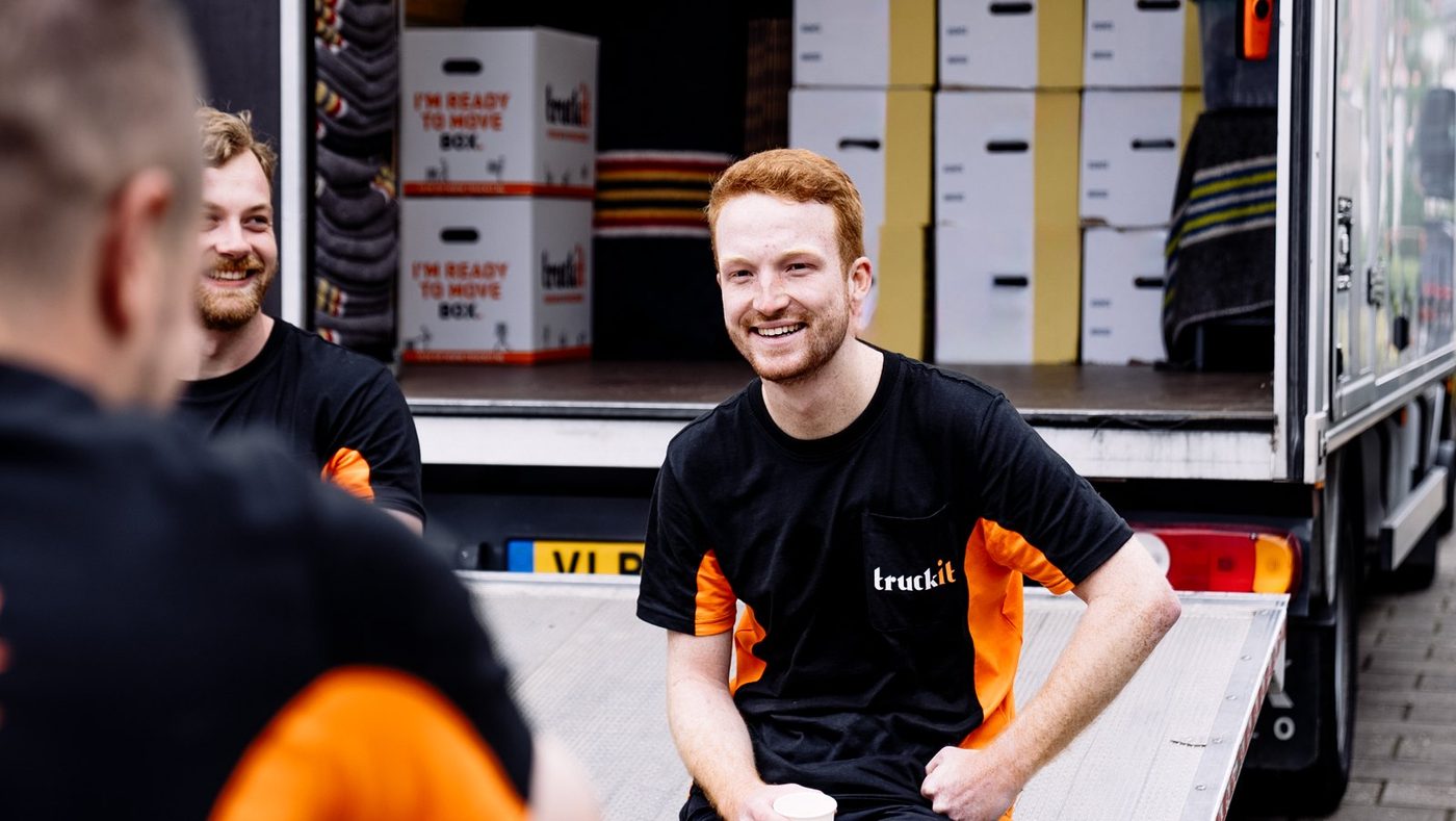 Lachende verhuizers van Truckit bij de open verhuiswagen