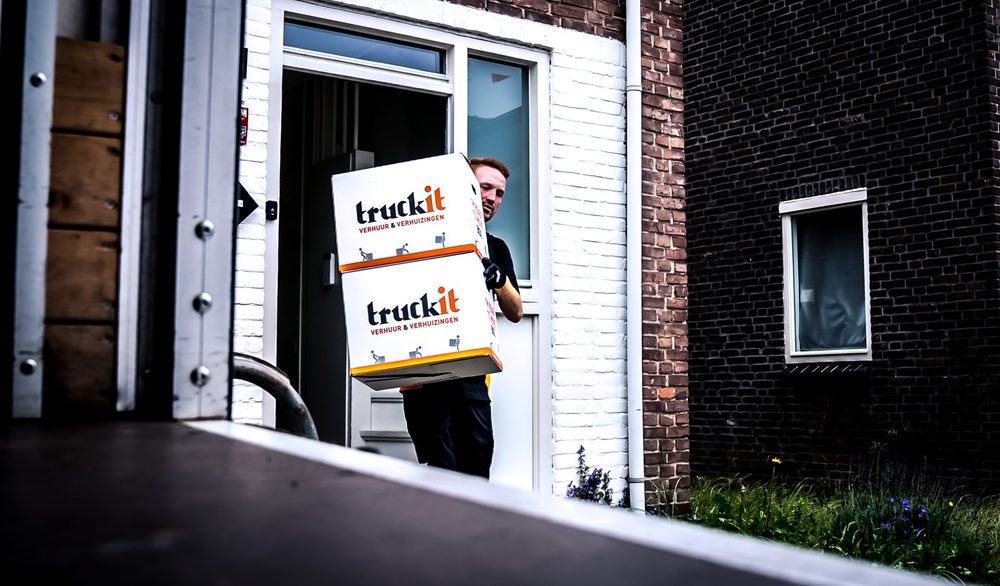Verhuizer van Truckit draagt twee verhuisdozen naar buiten
