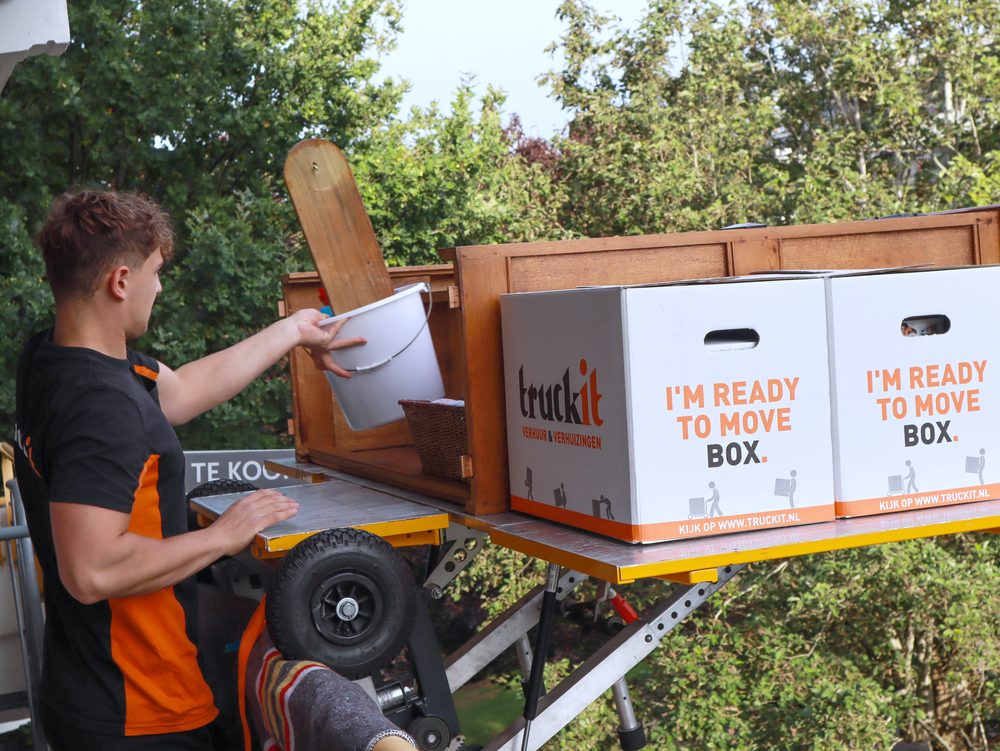Verhuizer van Truckit bij de verhuislift met verhuisdozen op het plateau