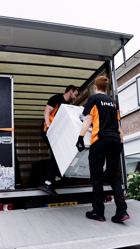 Twee verhuizers van Truckit tillen een wasmachine de verhuiswagen in